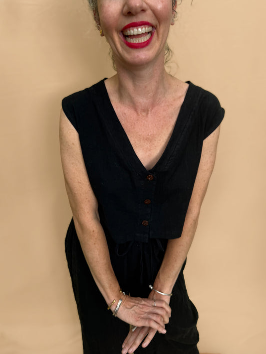 Woman wearing a black top and wide leg trousers with a beige background