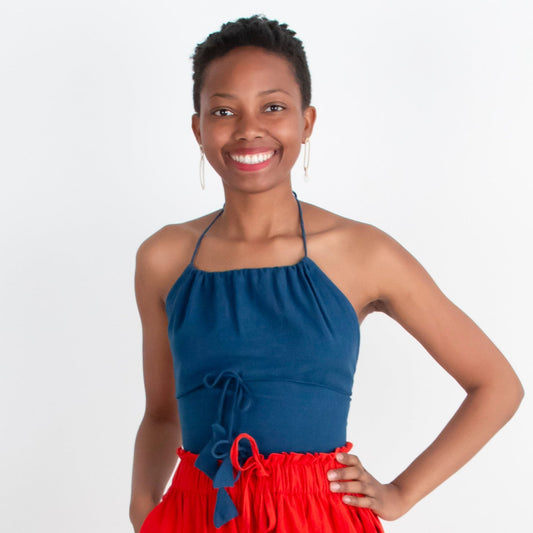 Woman wearing a blue top and red pants standing on a white background