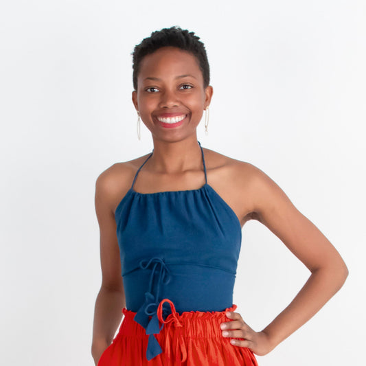 Woman wearing a blue top and red pants standing on a white background