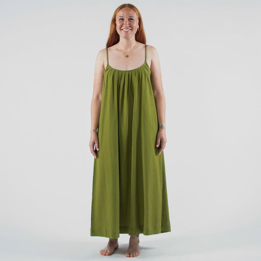 Woman wearing a green dress standing in a photo studio with equipment around.