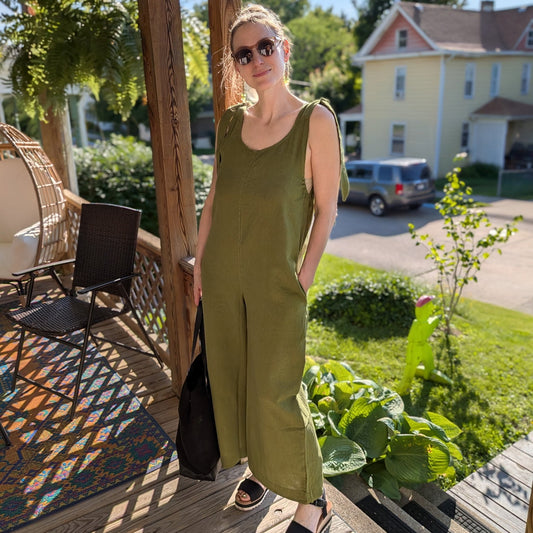 Woman in a green jumpsuit standing on a wooden deck with a suburban background