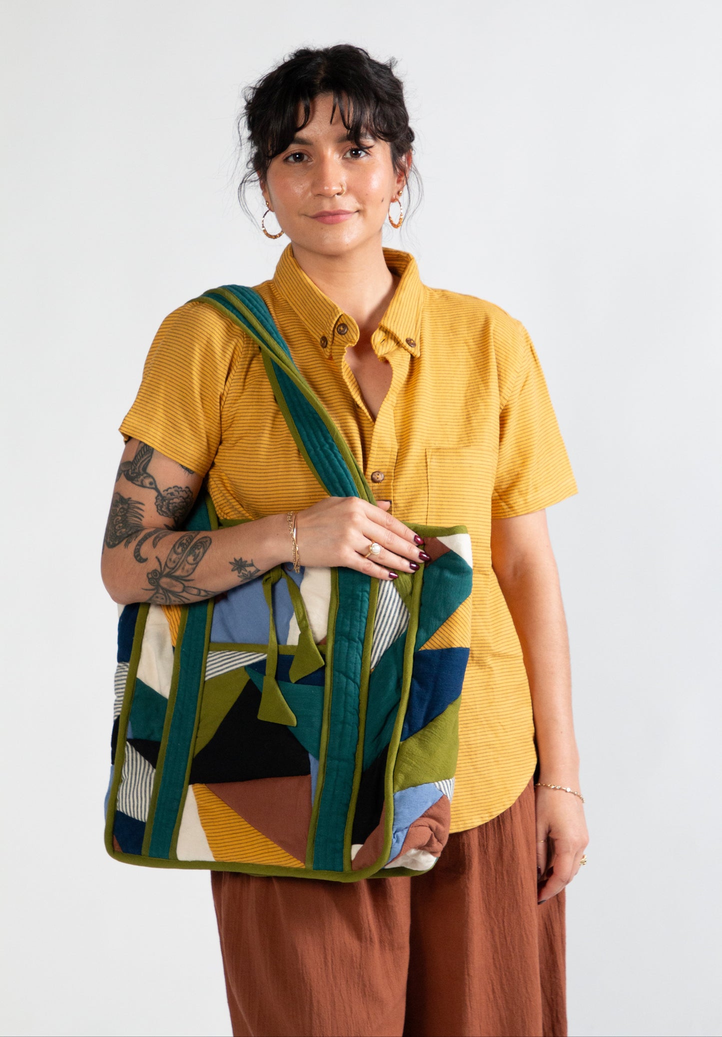 Woman holding a colorful patchwork bag against a white background