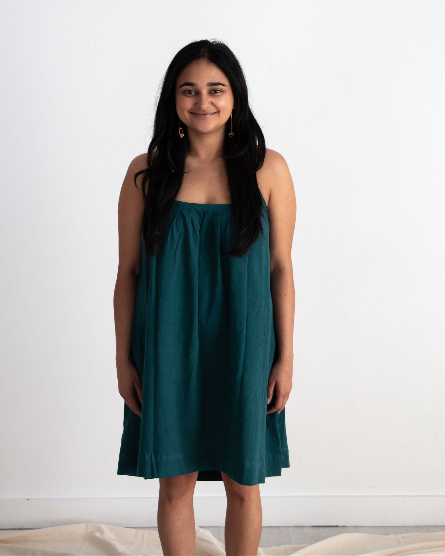 Woman wearing a teal dress against a white background