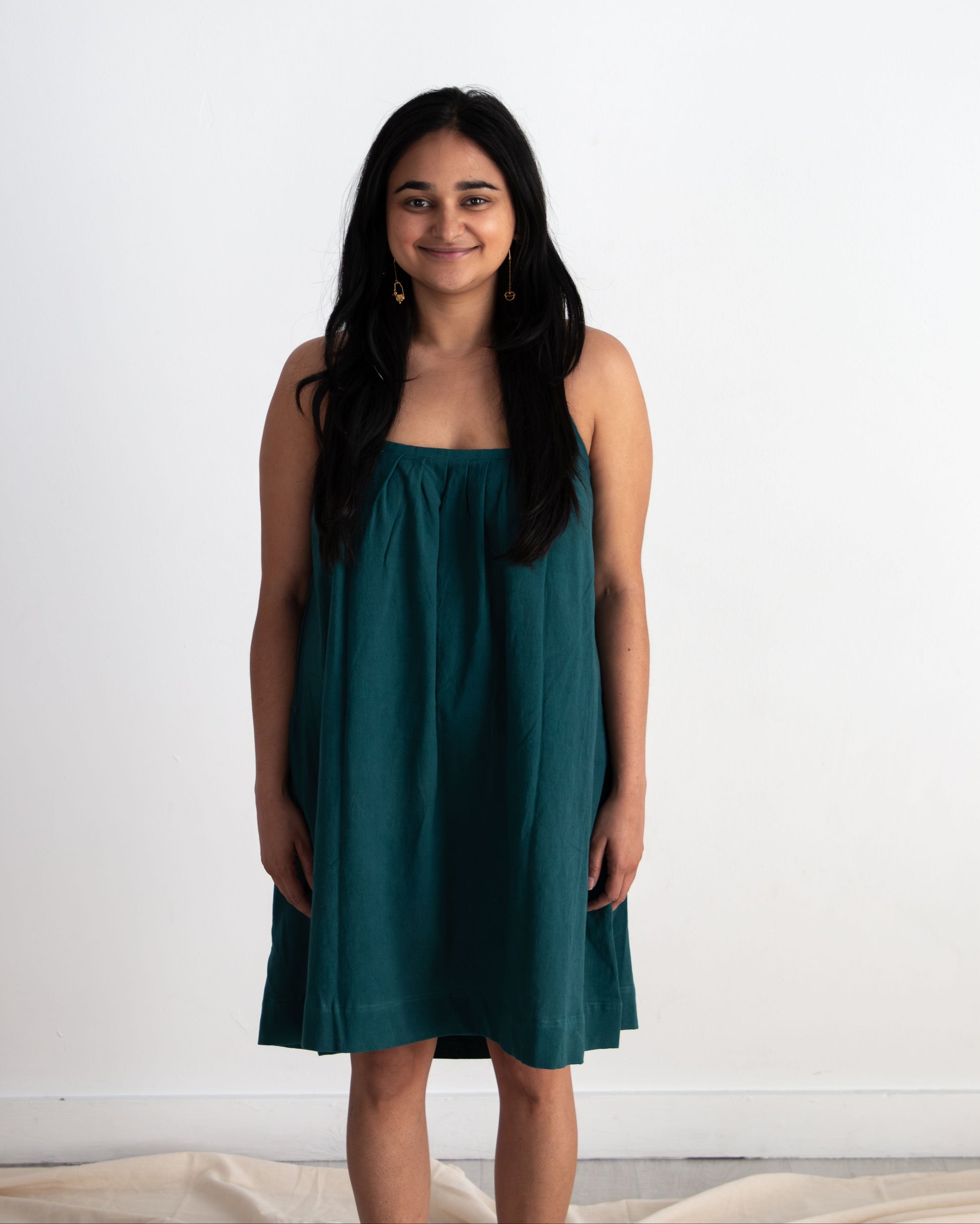 Woman wearing a teal dress against a white background