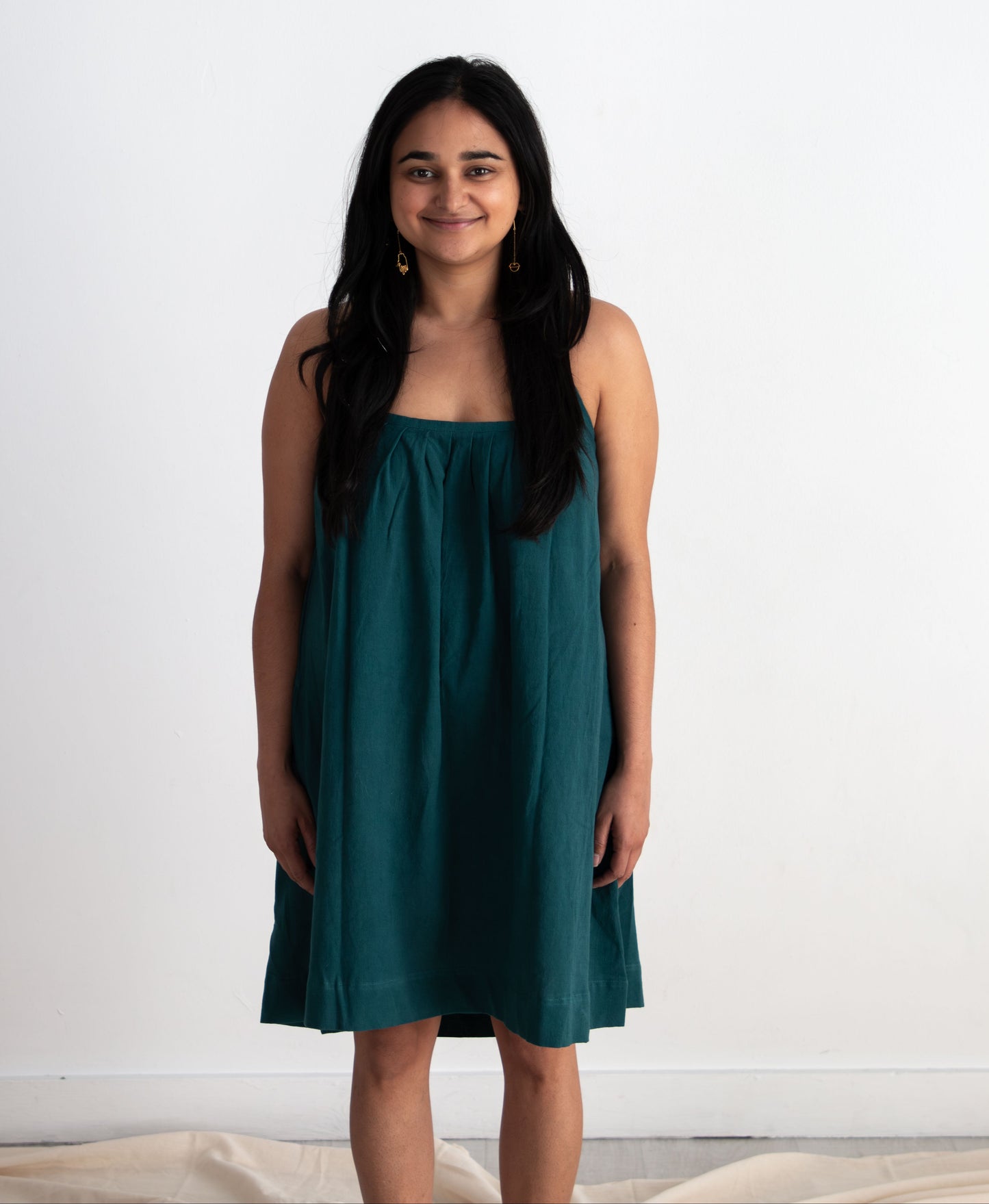 Woman wearing a teal dress against a white background