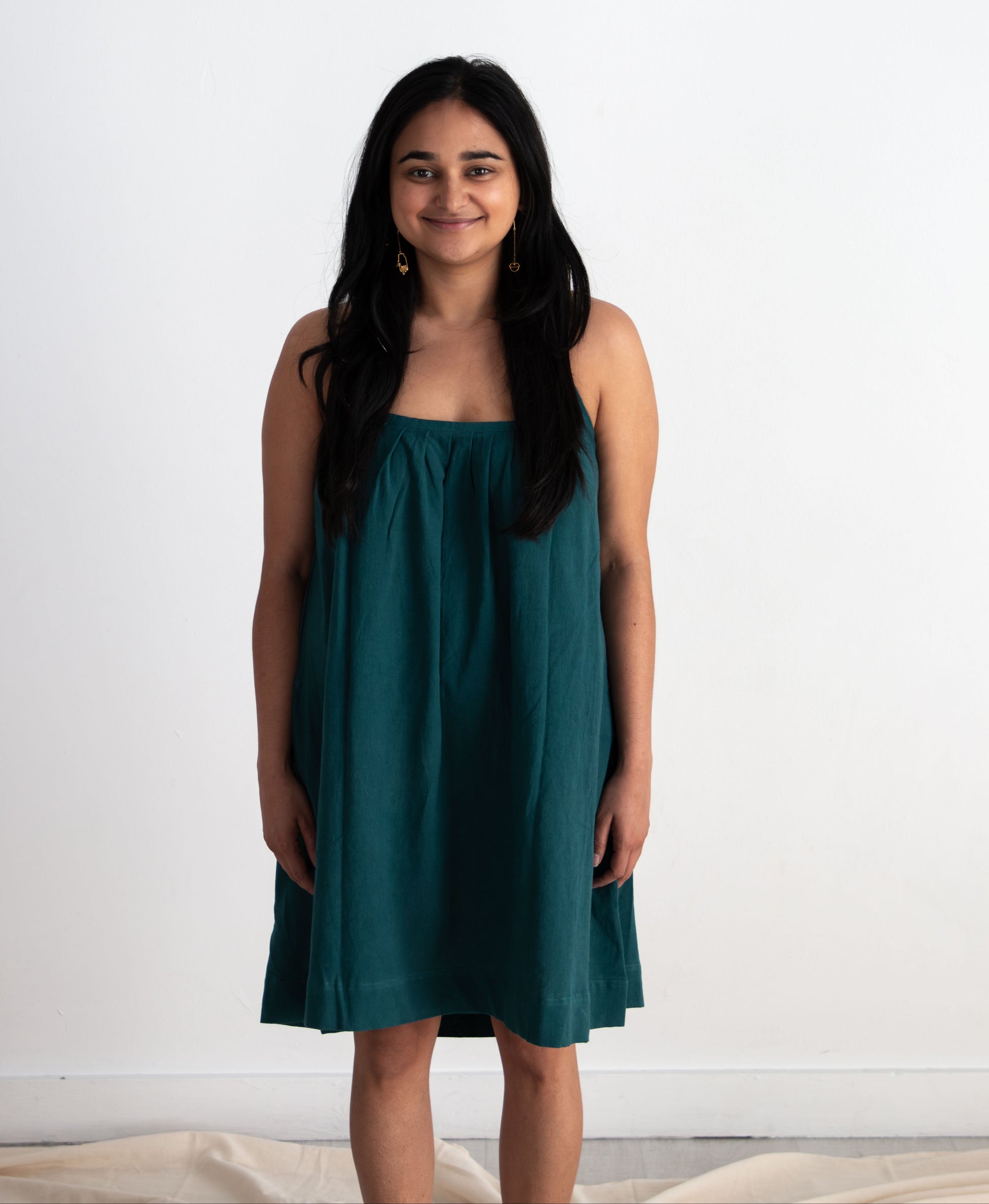 Woman wearing a teal dress against a white background