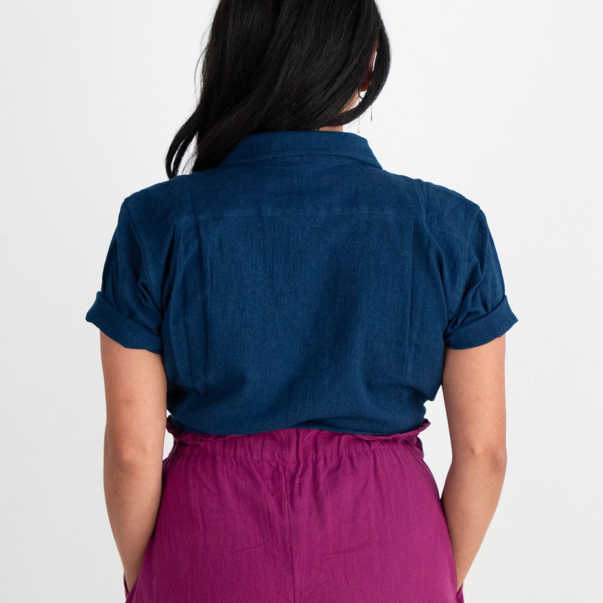 Person wearing a blue shirt and purple pants on a white background