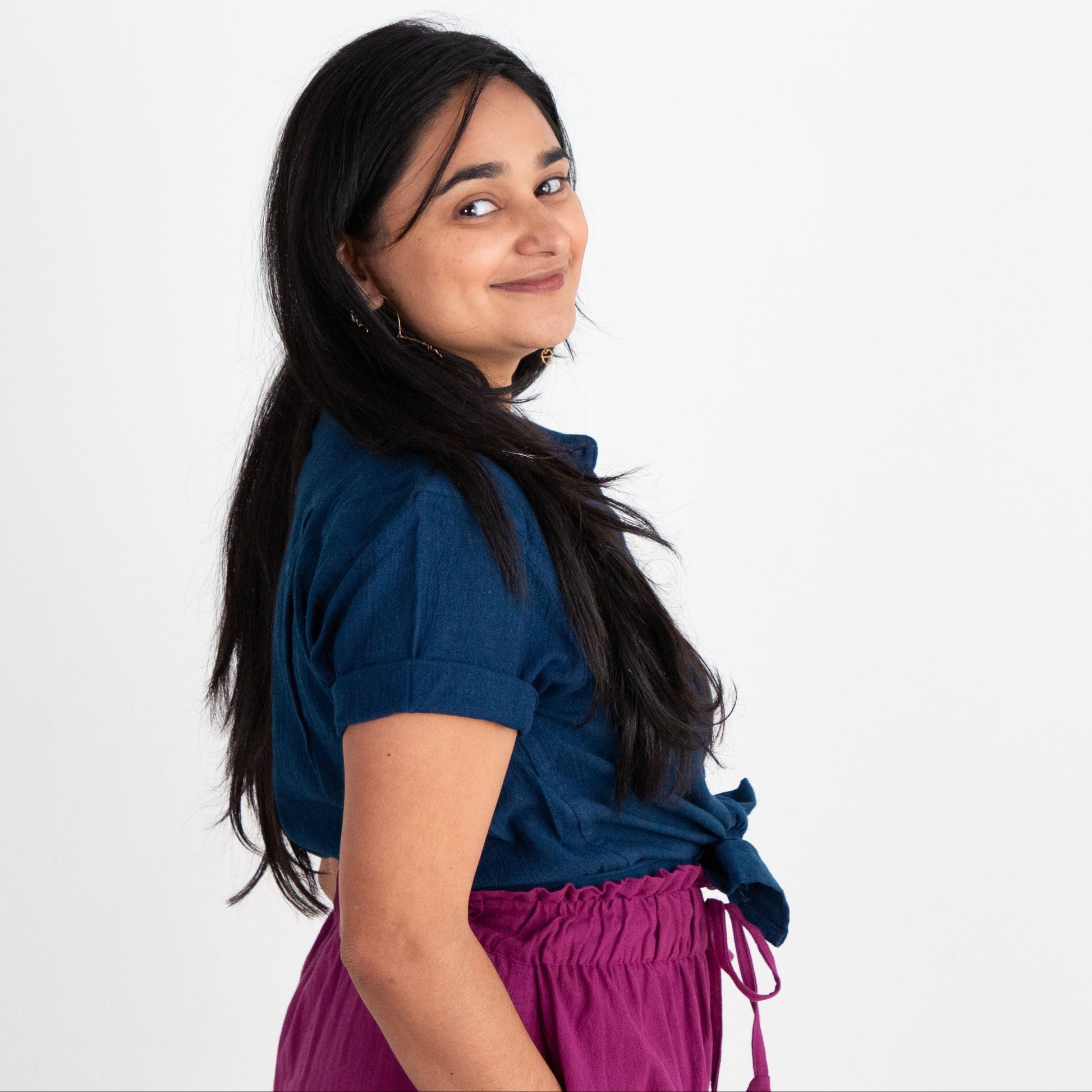 Woman wearing a blue shirt and purple pants on a white background
