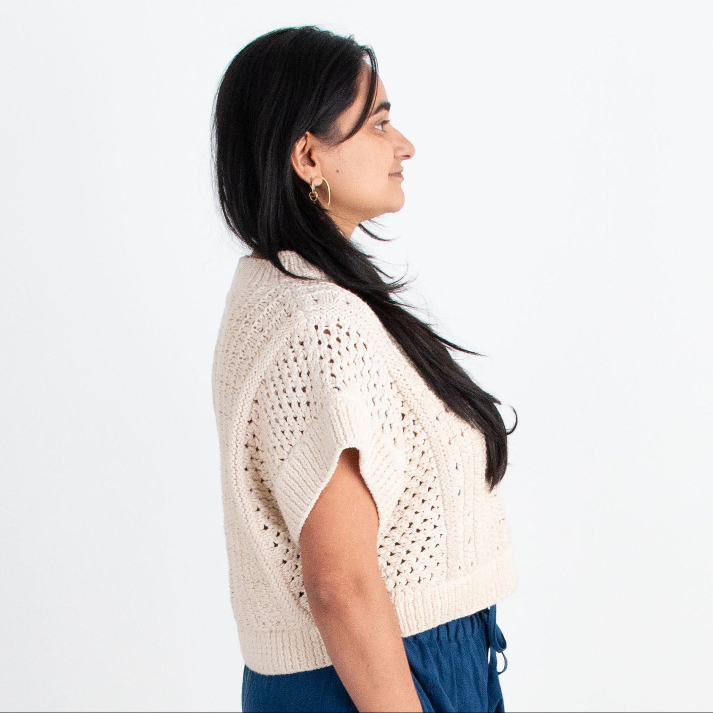 Woman wearing a white top and blue pants standing on a white background