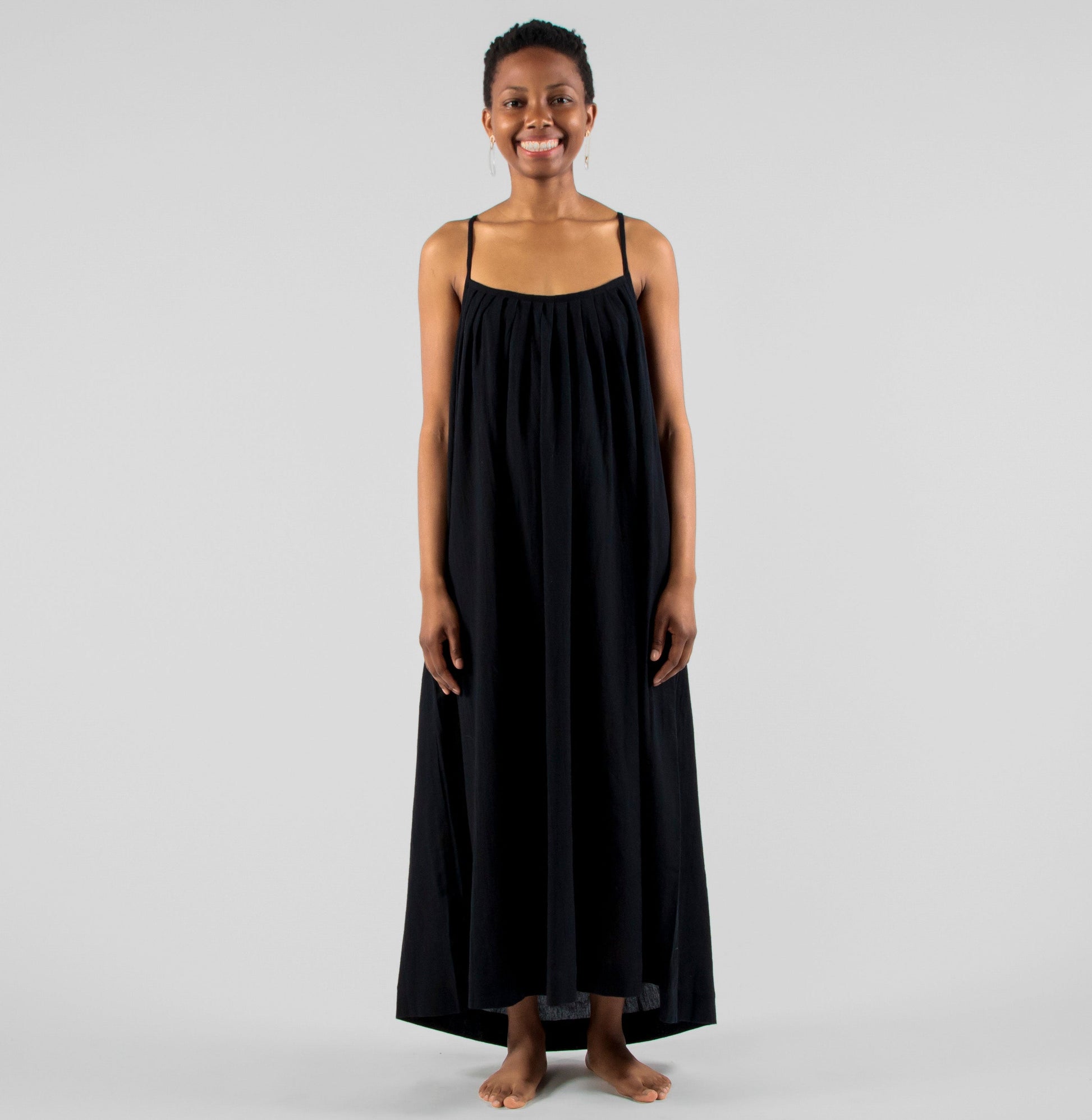 Woman wearing a black dress standing on a white background in a studio setting