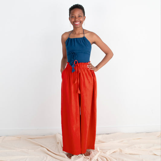 Woman wearing a blue top and red pants standing on a white background