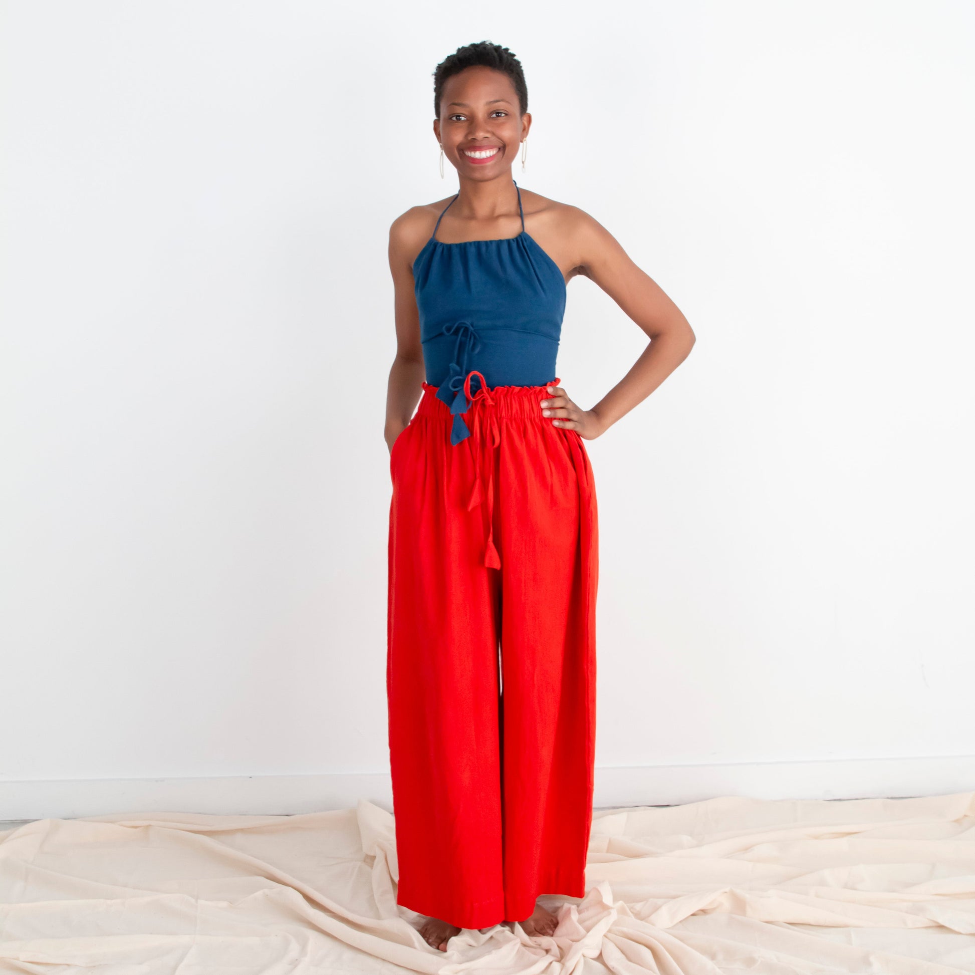 Woman wearing a blue top and red pants standing on a white background