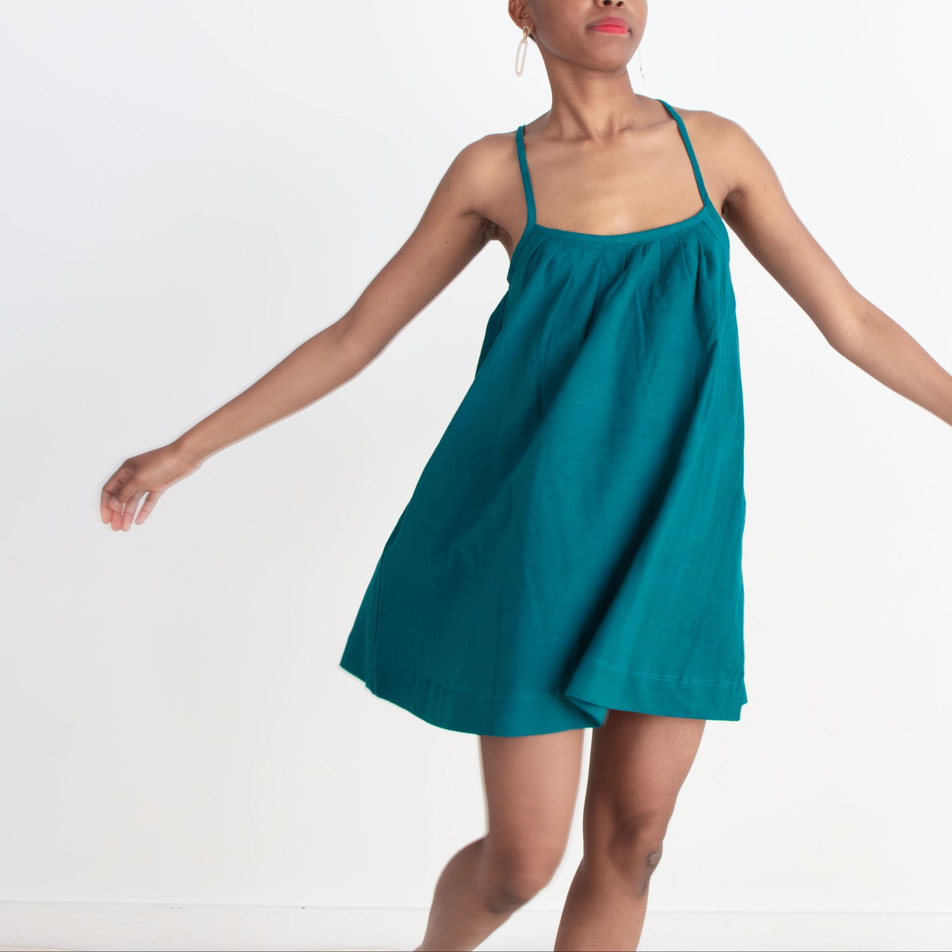 Woman wearing a teal dress against a white background