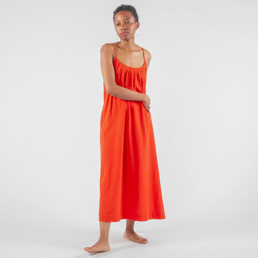Woman in a red dress standing on a white background in a studio setting