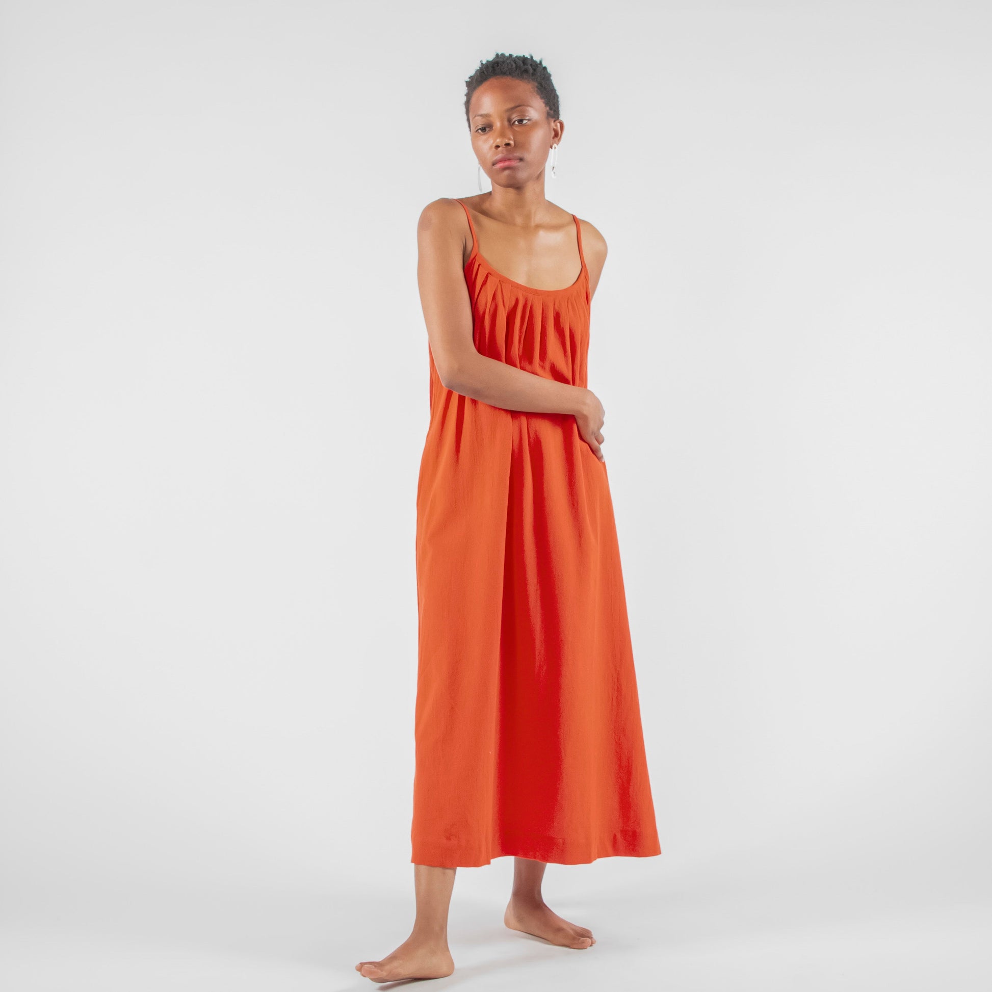 Woman in a red dress standing on a white background in a studio setting