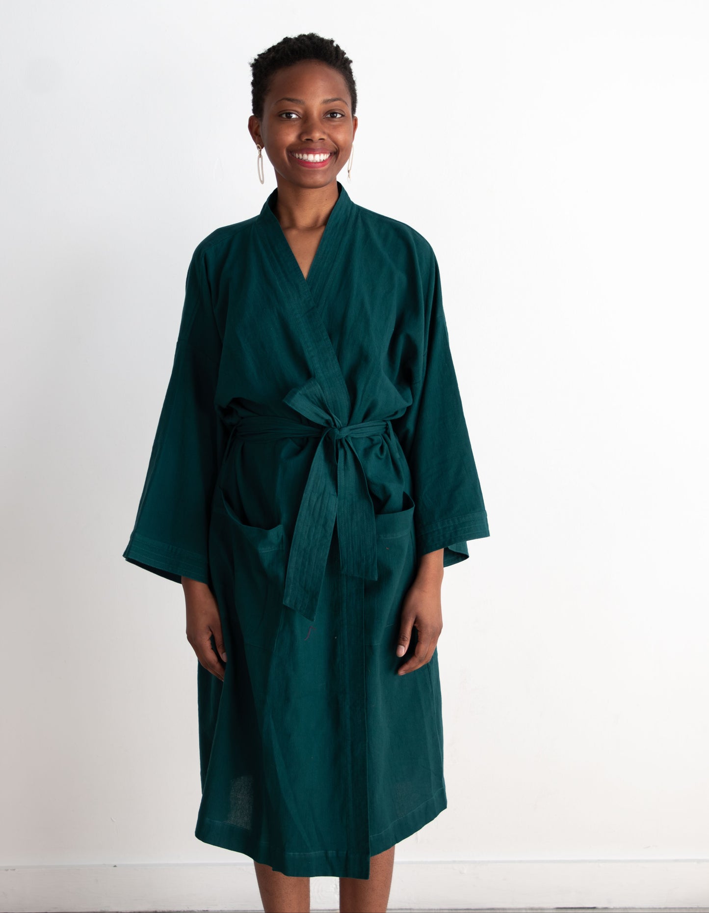 Woman wearing a teal robe against a white background