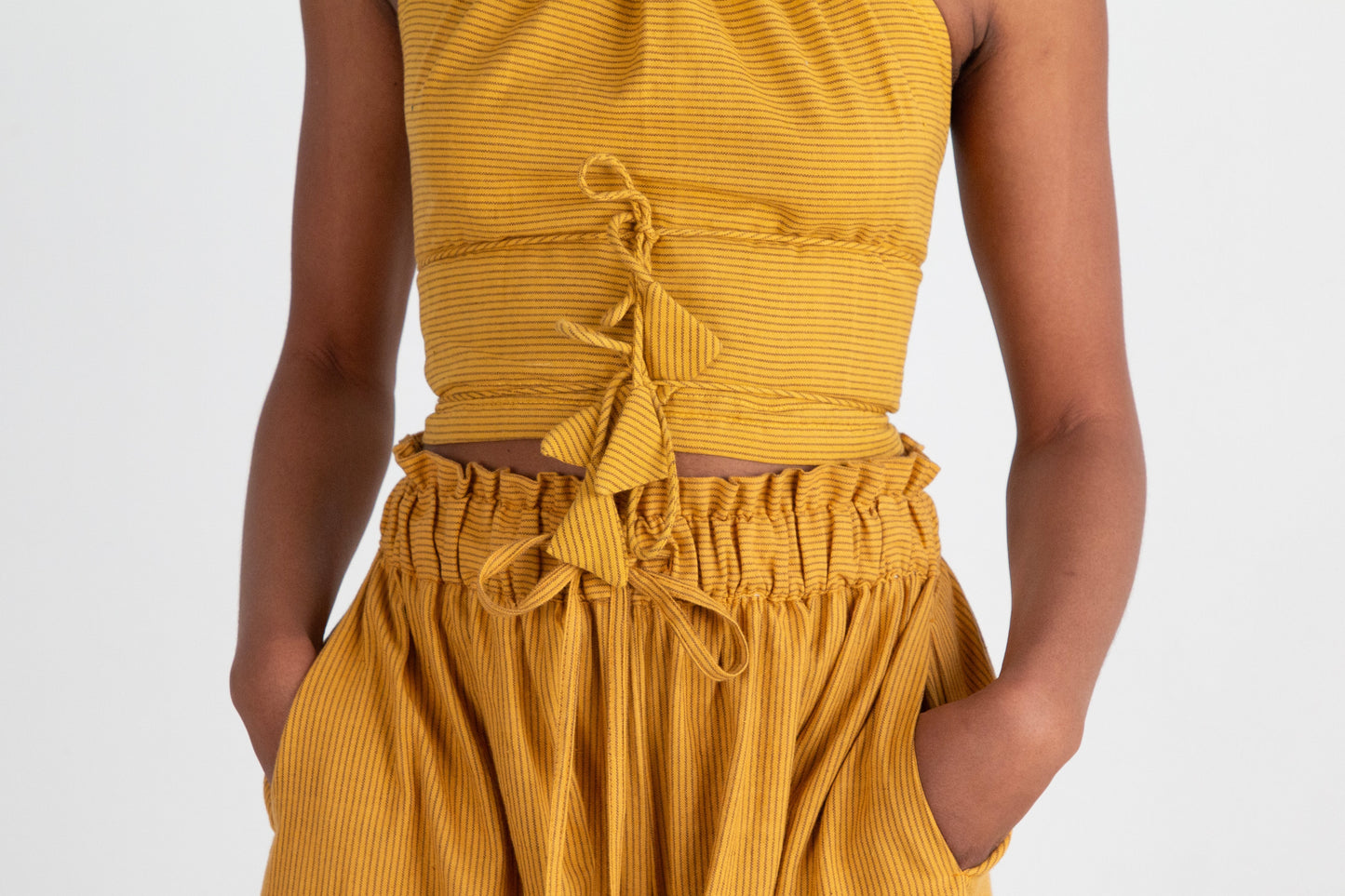 Mustard yellow sleeveless top and high-waisted pants on a plain background