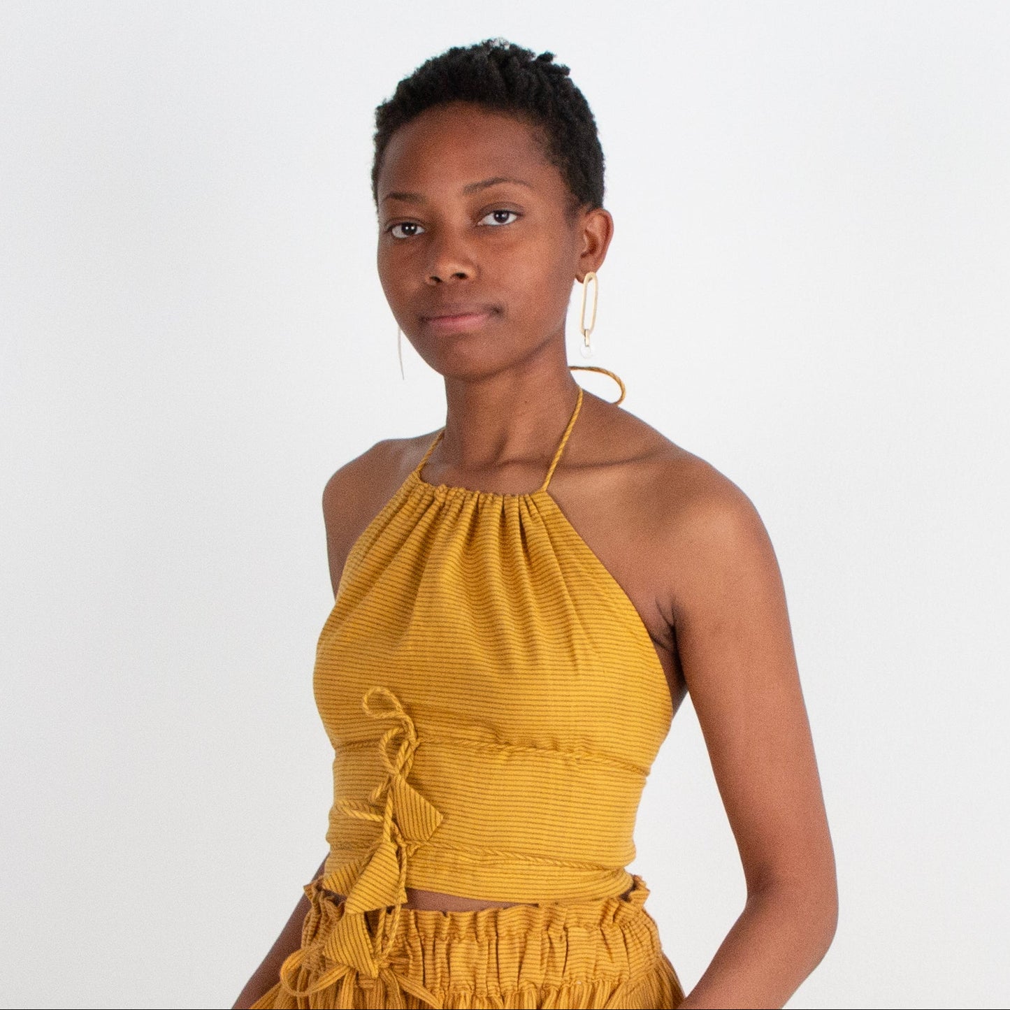 Woman wearing a mustard yellow top against a white background