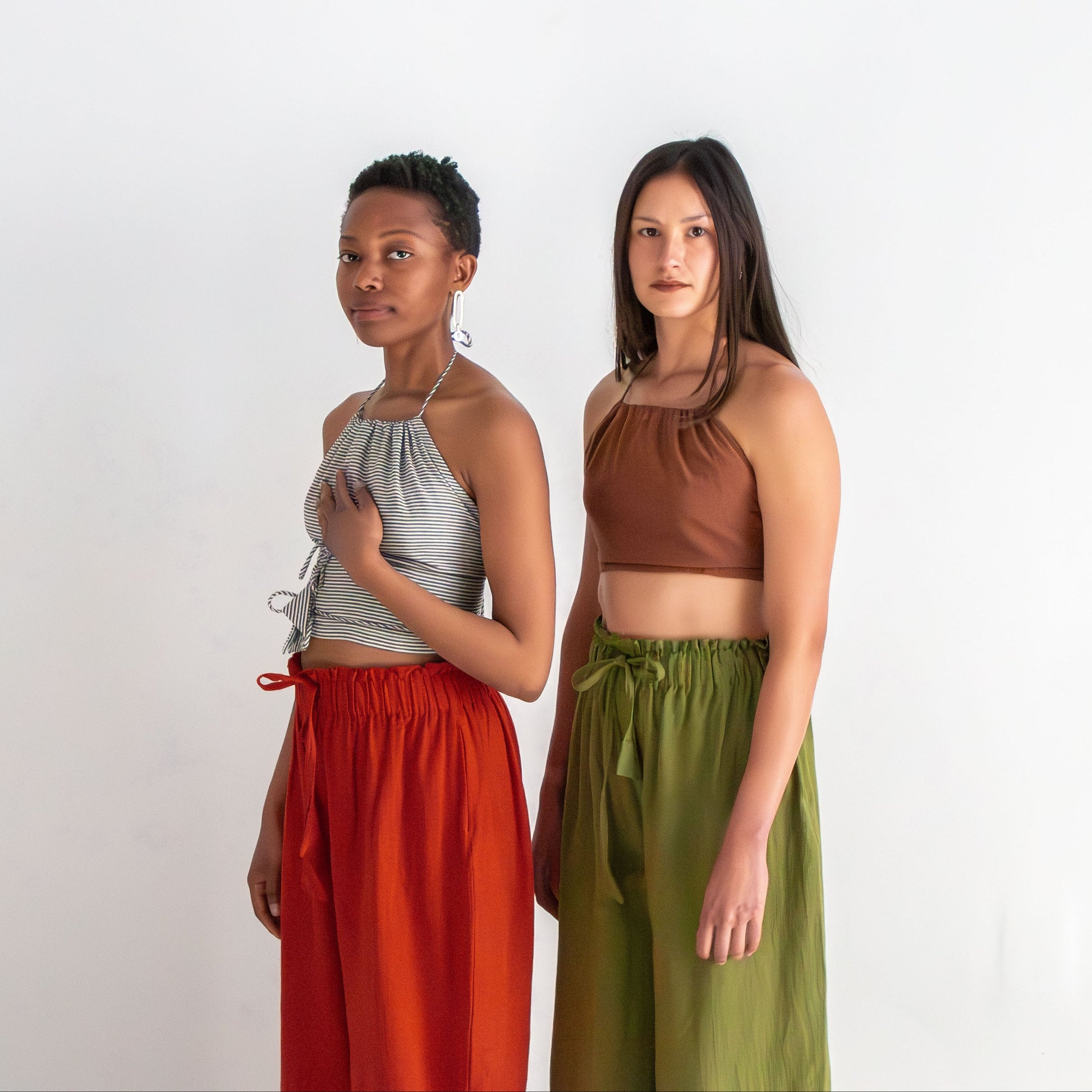 Two women standing side by side wearing colorful outfits on a white background
