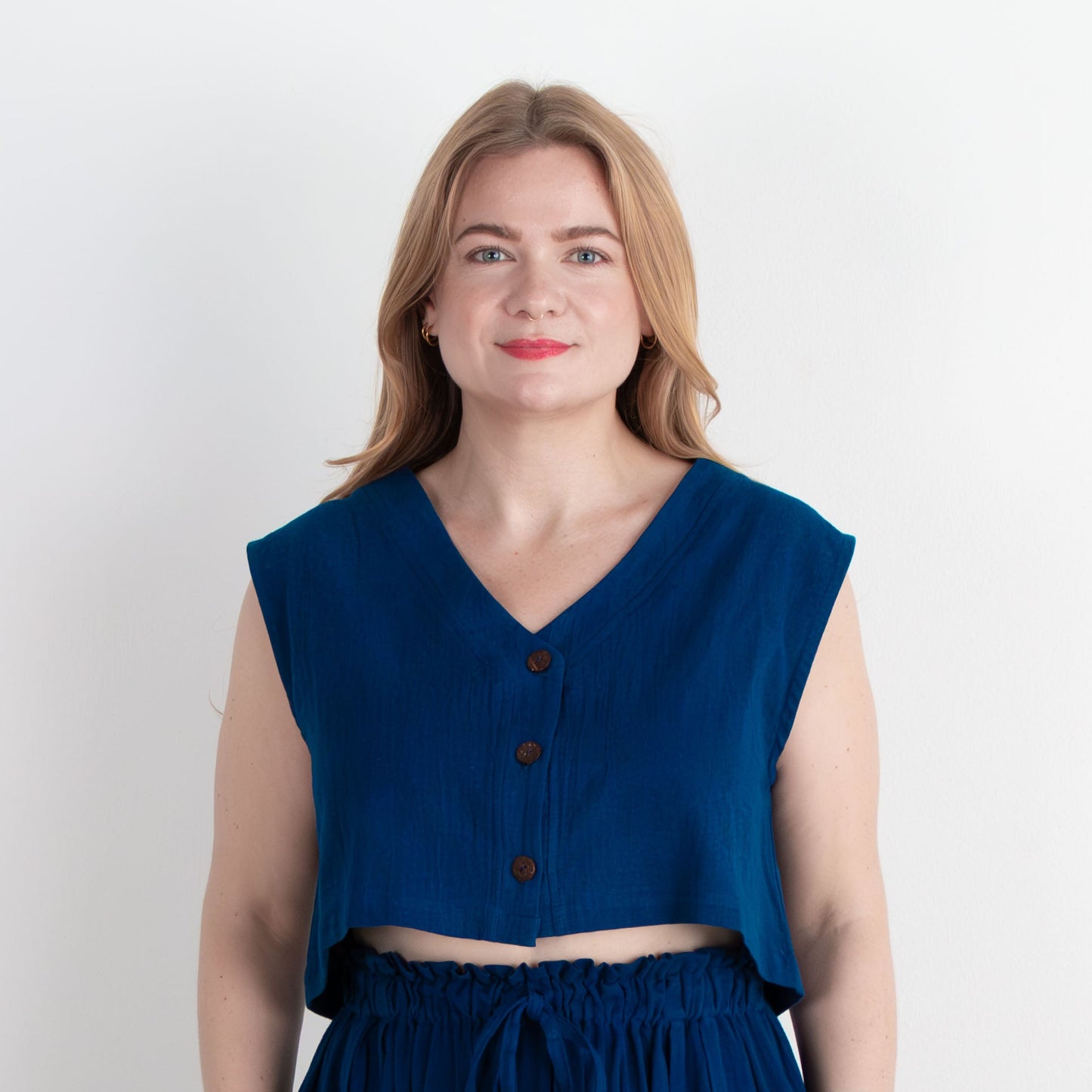 Woman wearing a blue sleeveless top and long skirt against a white background