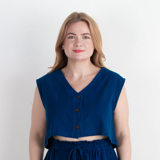 Woman wearing a blue sleeveless top and long skirt against a white background