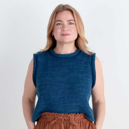 Woman wearing a blue sleeveless top and brown wide-leg pants on a white background