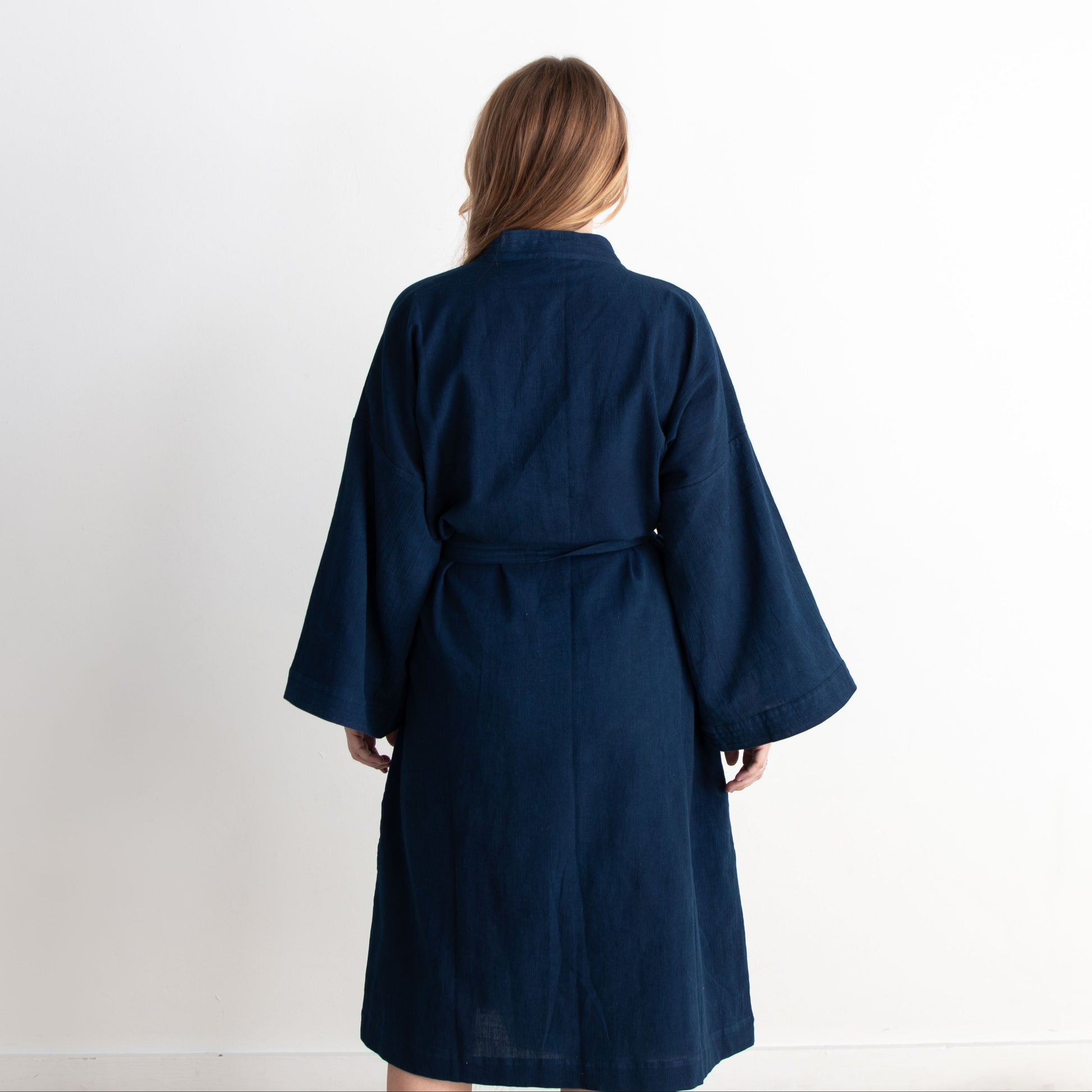 Person wearing a navy blue robe against a white background