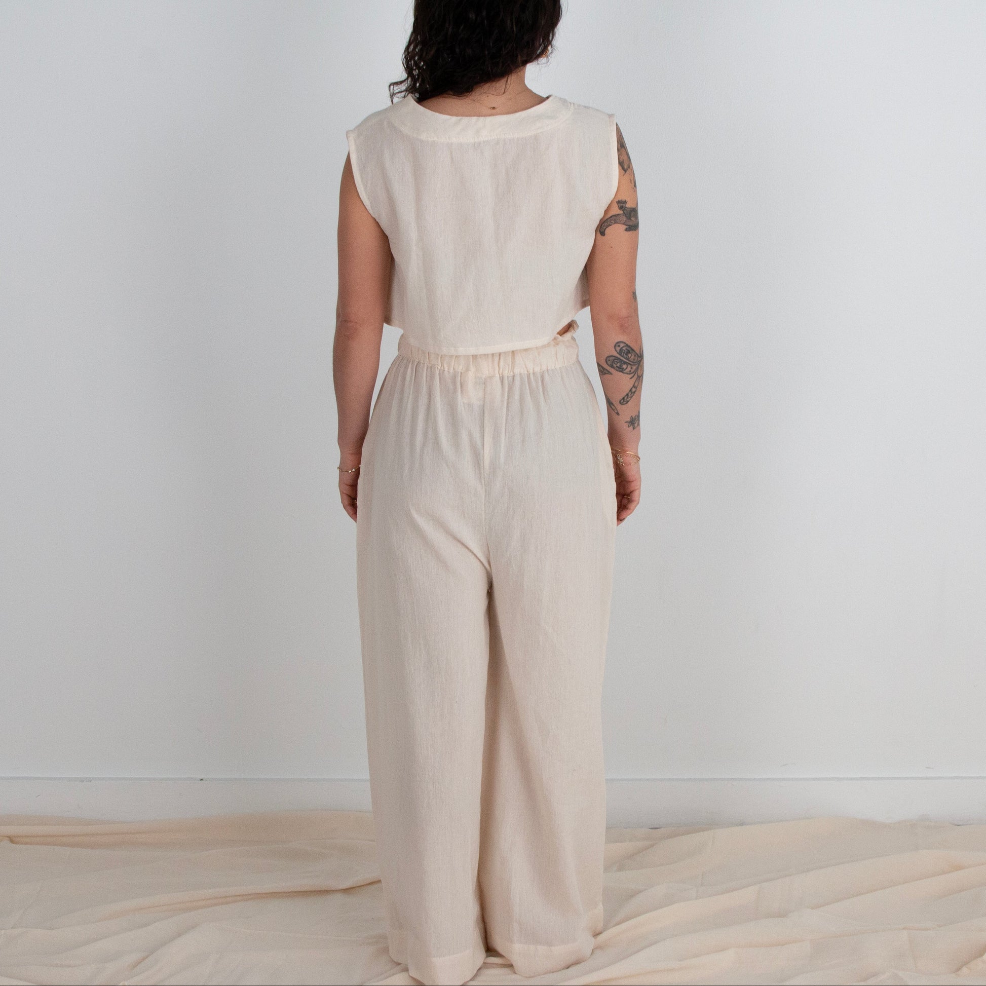 Person wearing a beige outfit standing against a white background