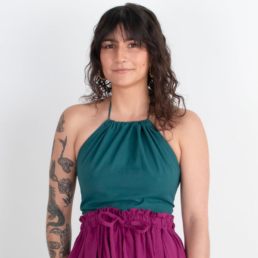 Woman wearing a teal top and magenta skirt against a white background