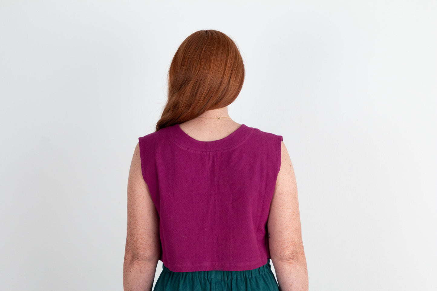 Person wearing a purple sleeveless top with a plain background