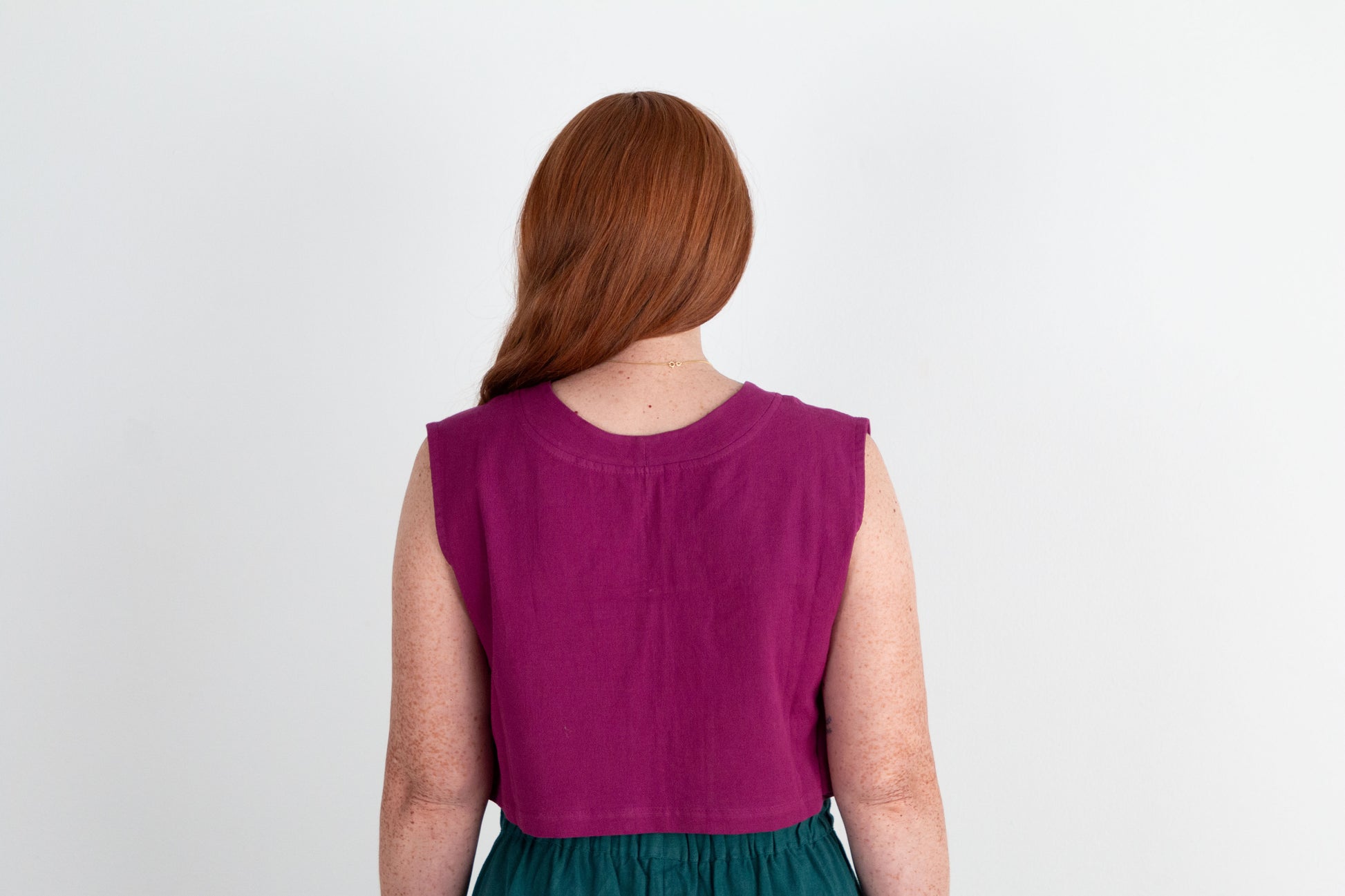 Person wearing a purple sleeveless top with a plain background