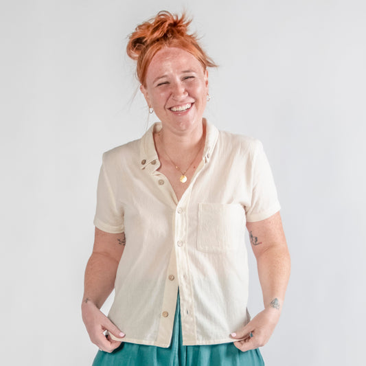 Person wearing a white shirt and teal pants on a plain background