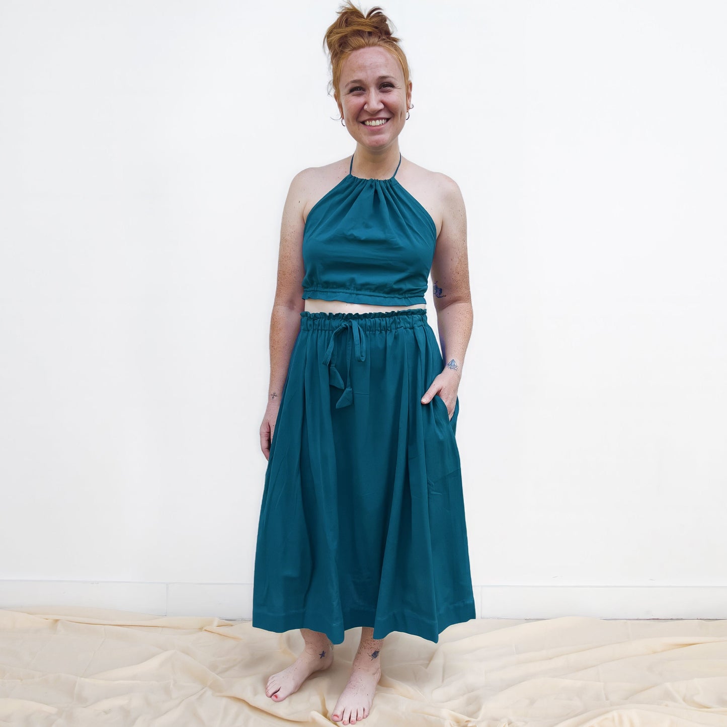 Woman wearing a teal dress standing on a white background