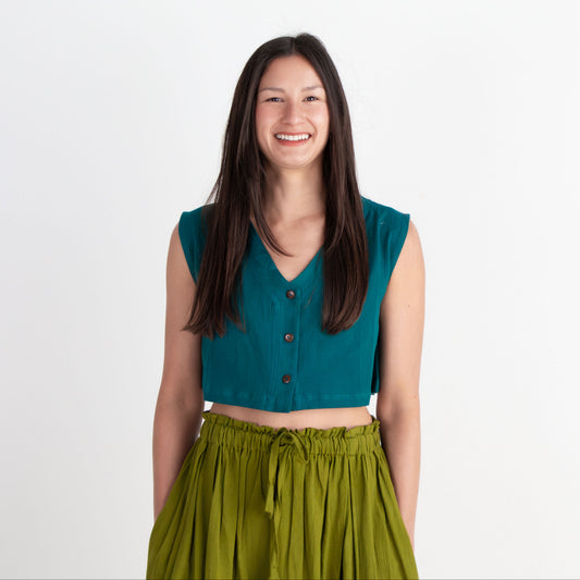 Woman wearing a teal top and green skirt on a white background