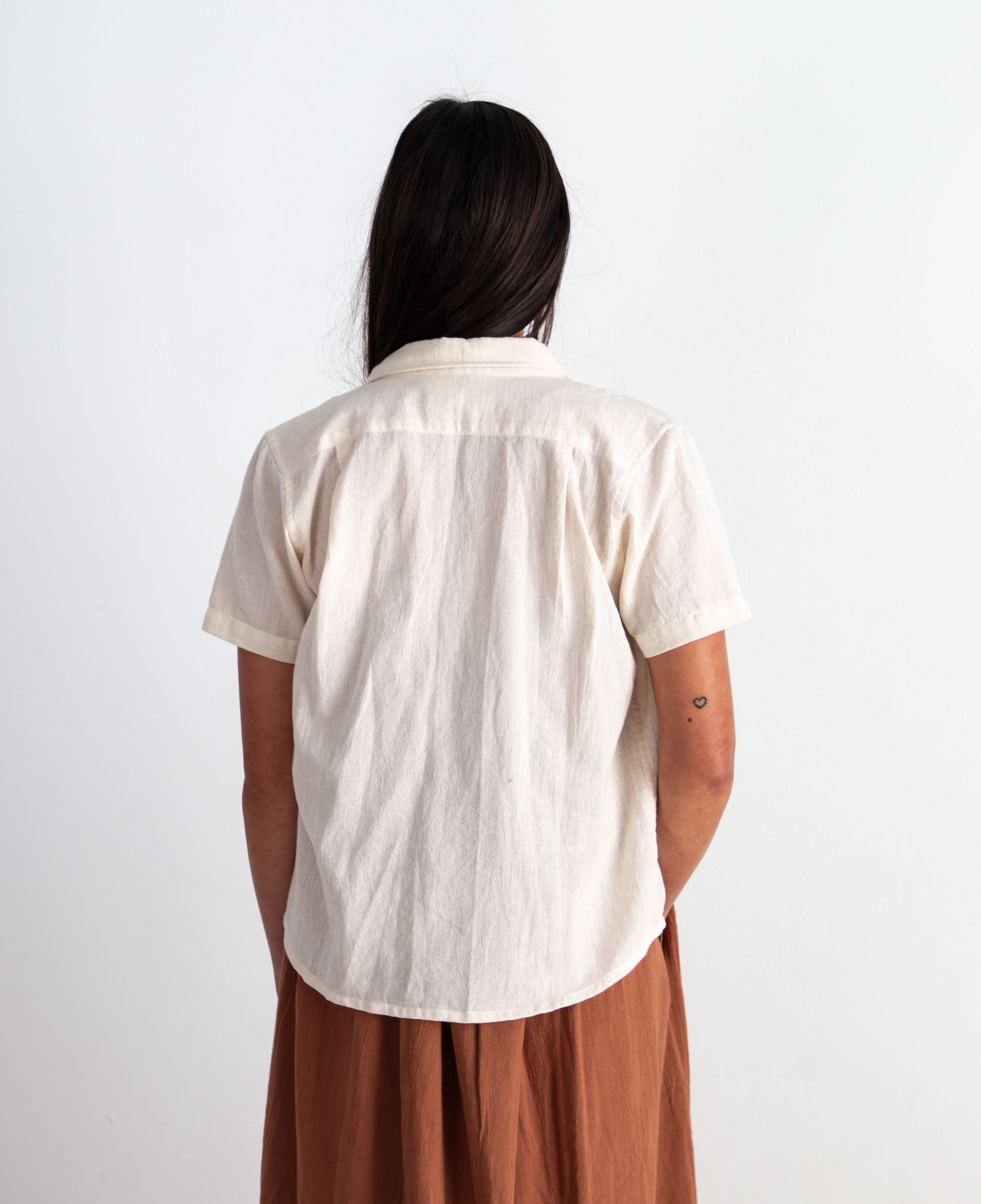 Person wearing a white shirt and brown dress against a white background