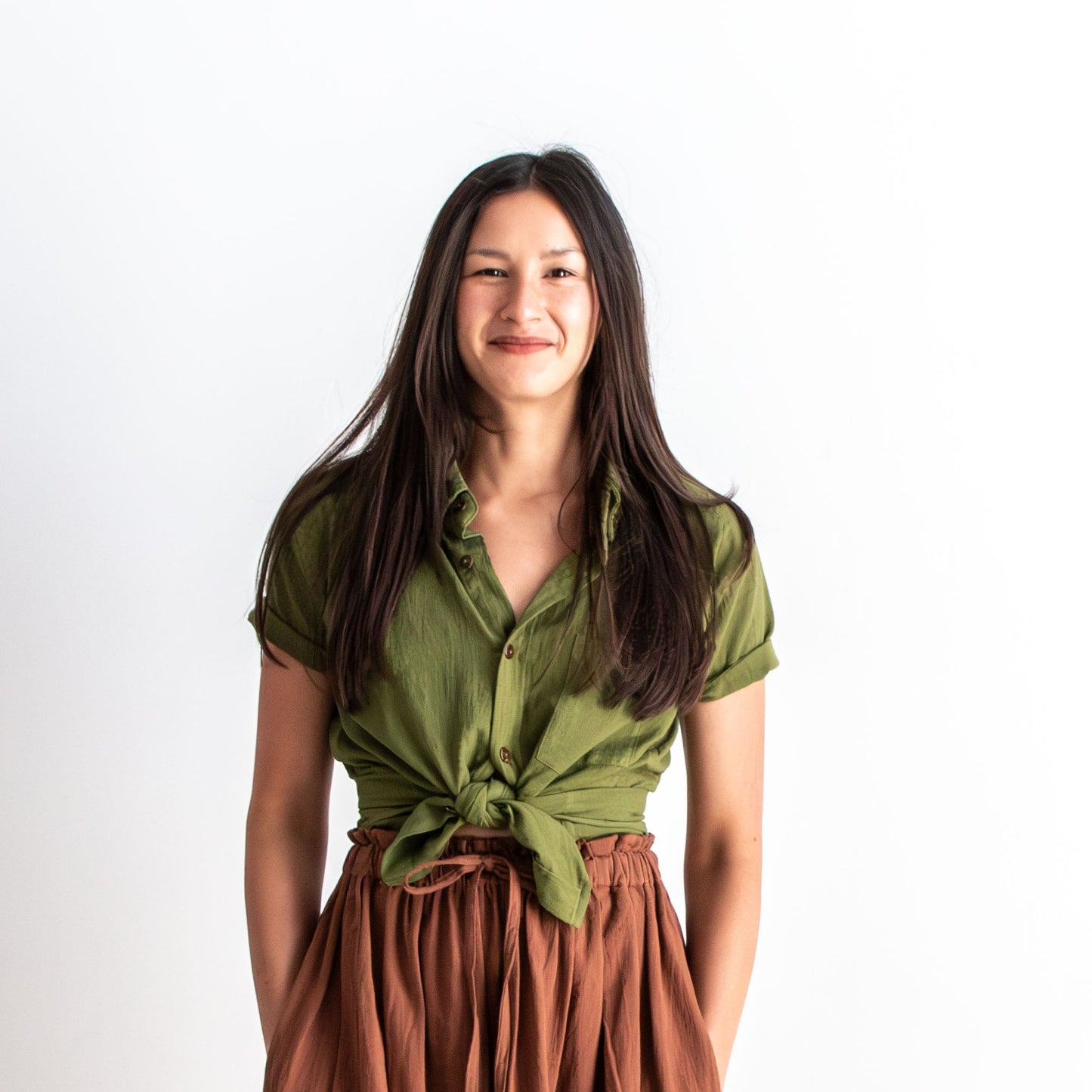Woman wearing a green top and brown skirt on a white background