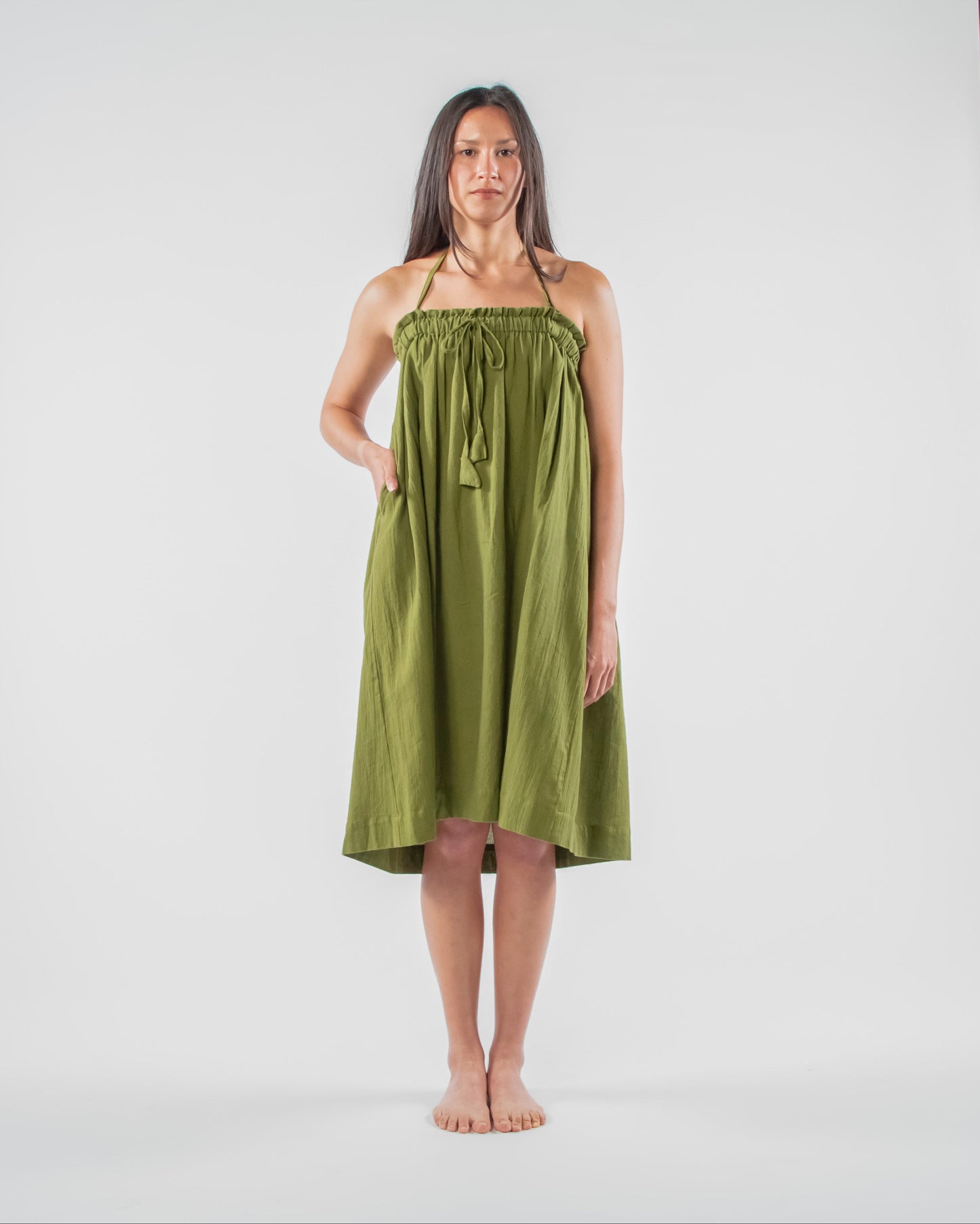 Woman wearing a green dress standing on a white background 