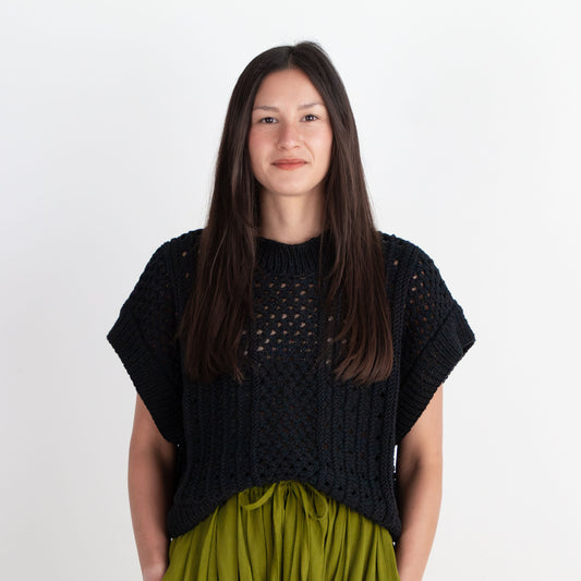 Woman wearing a black top and green skirt against a white background