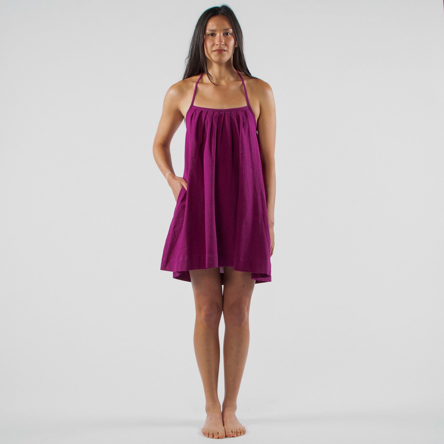 Woman wearing a purple dress standing in a studio setting with white backdrop