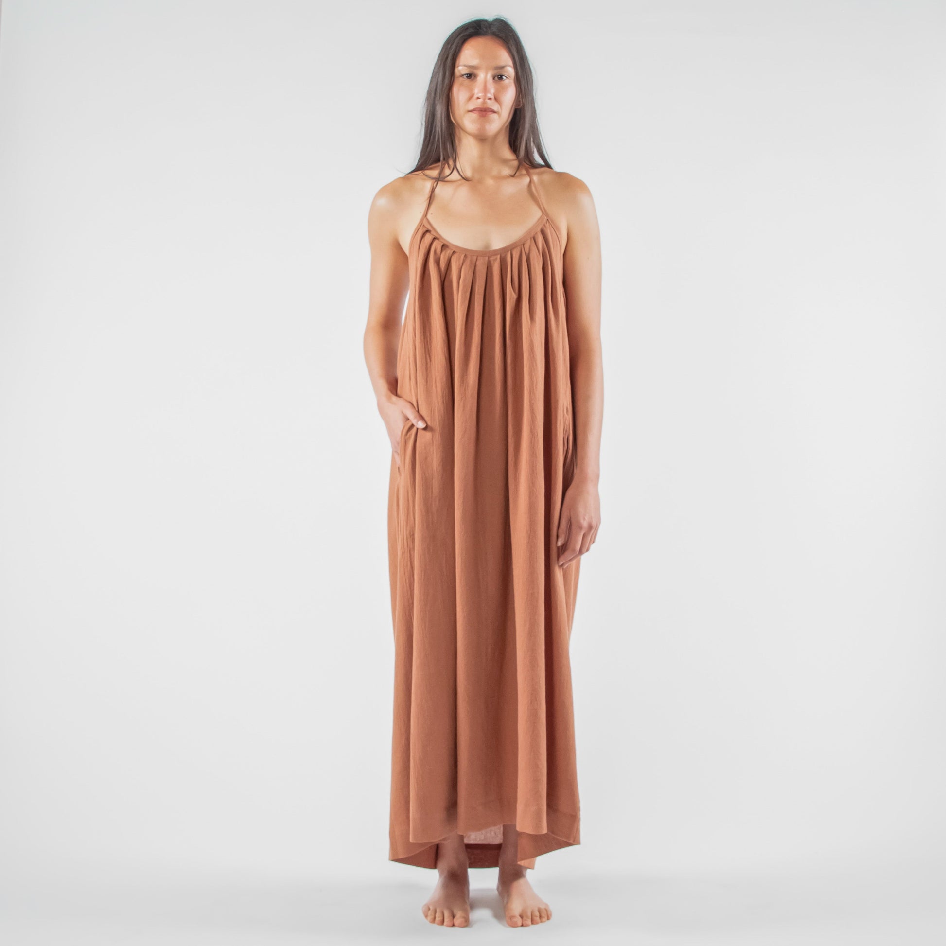 Woman wearing a brown dress standing in a studio setting 