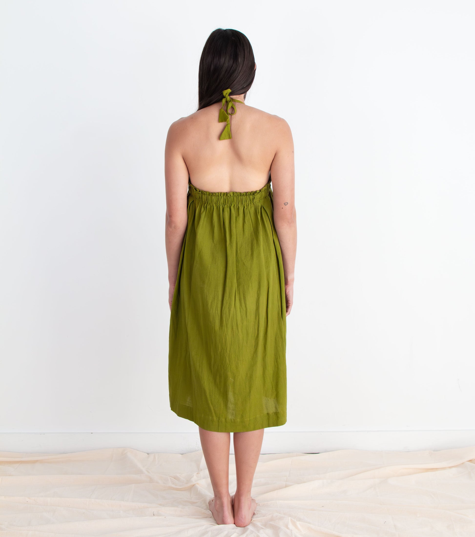 Woman wearing a green dress standing on a white floor with a white wall background