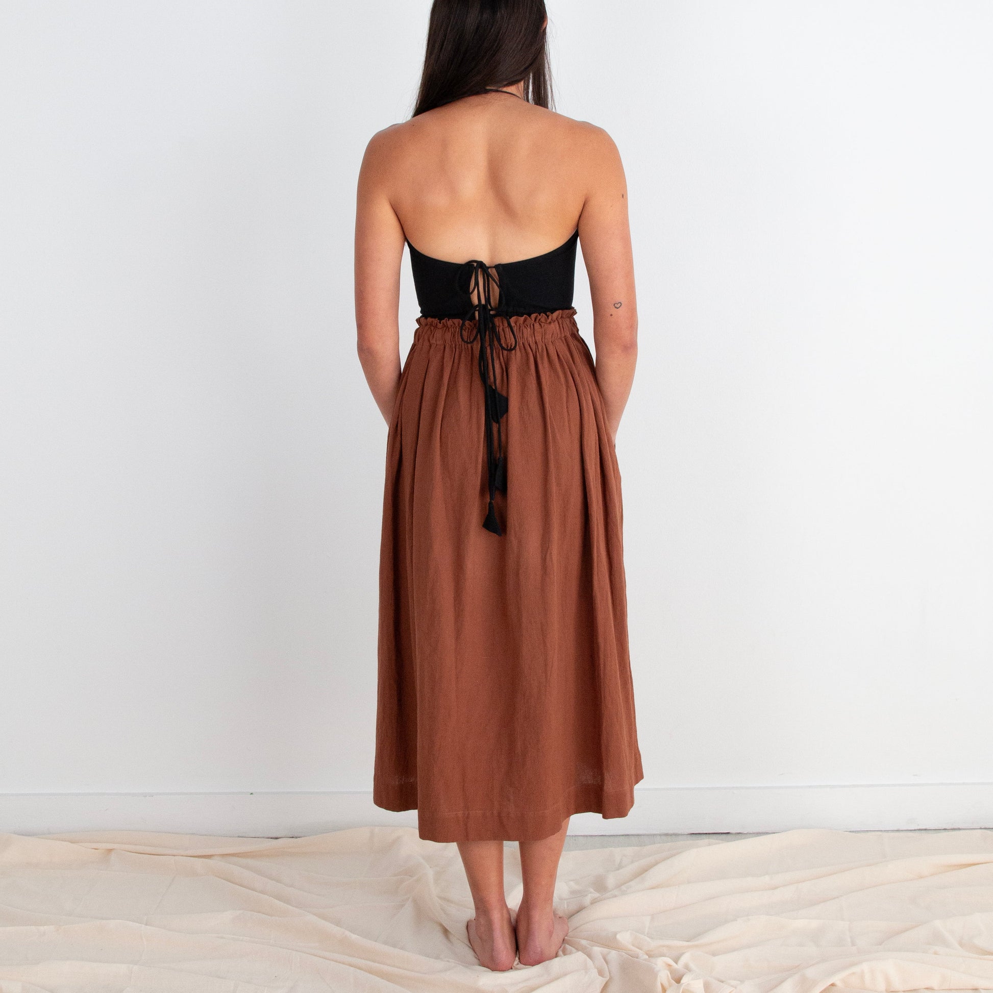 Woman wearing a strapless dress with a black top and brown skirt on a white background
