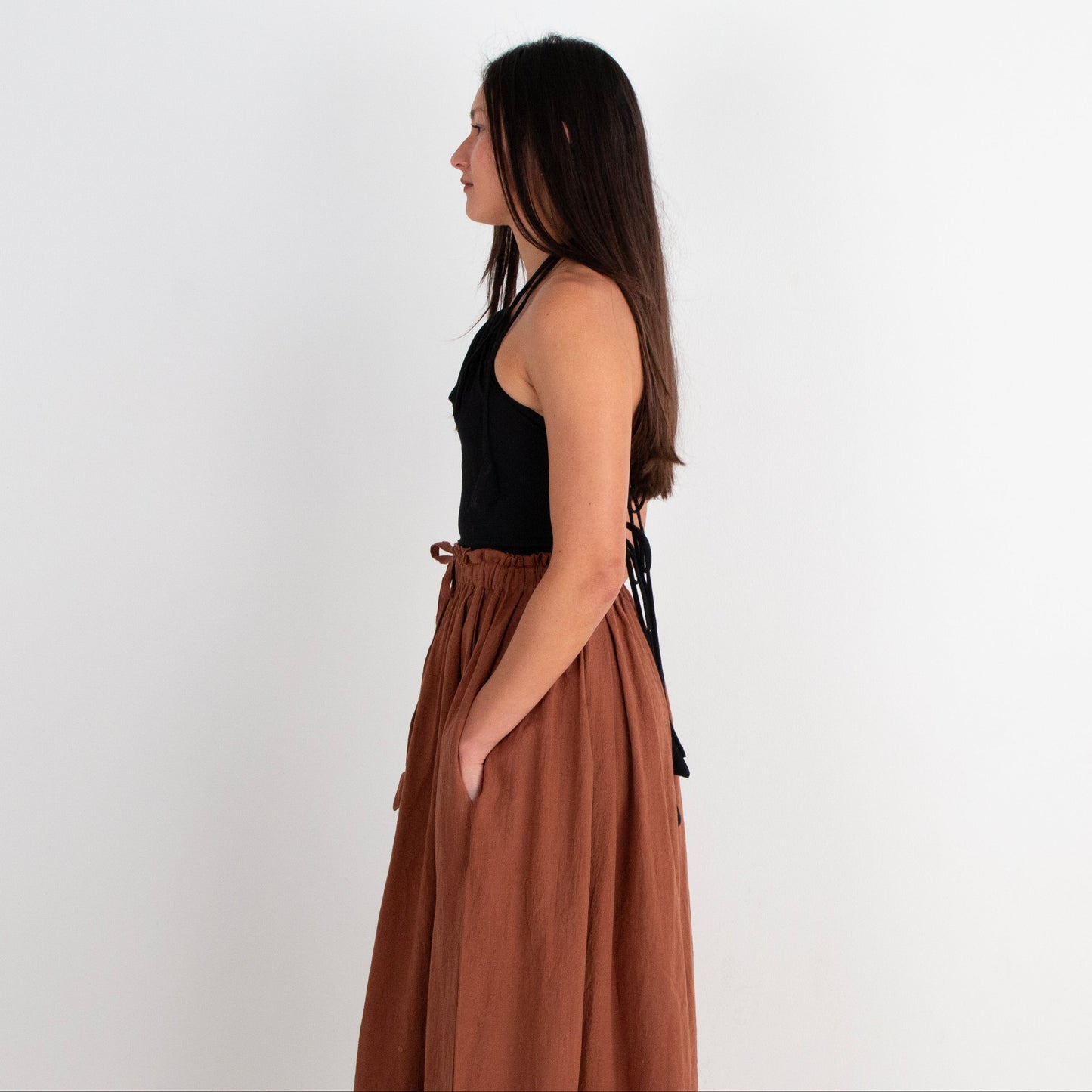 Woman wearing a black top and brown skirt on a white background