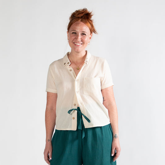 Woman wearing a white shirt and teal pants on a white background