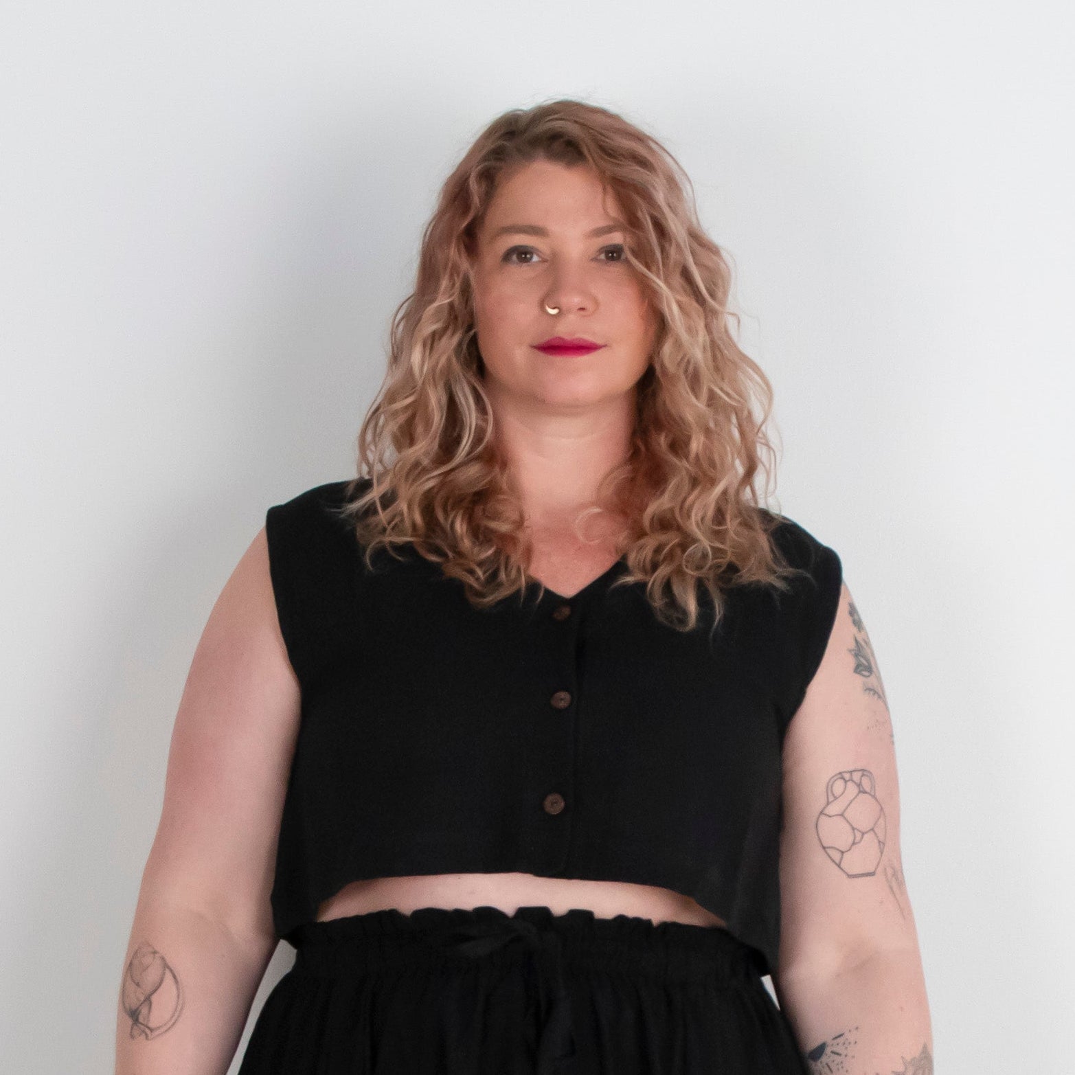 Woman wearing a black sleeveless top and black skirt against a white background